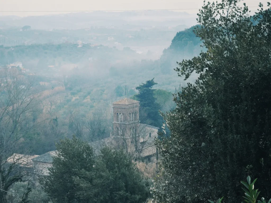 Abbazia di Palombara immersa nella natura e nella nebbia, vista panoramica tra alberi e antiche architetture